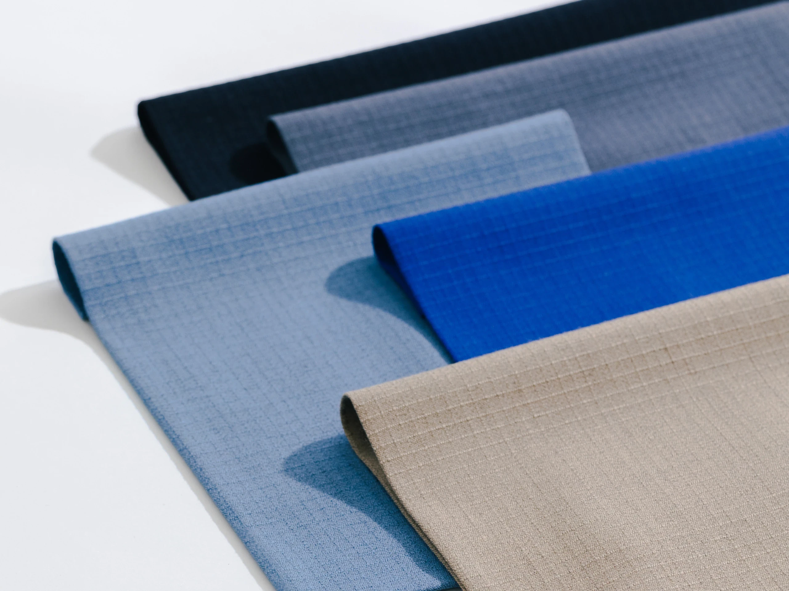 Folded MARKO AS flame-resistant fabrics in blue, gray and beige